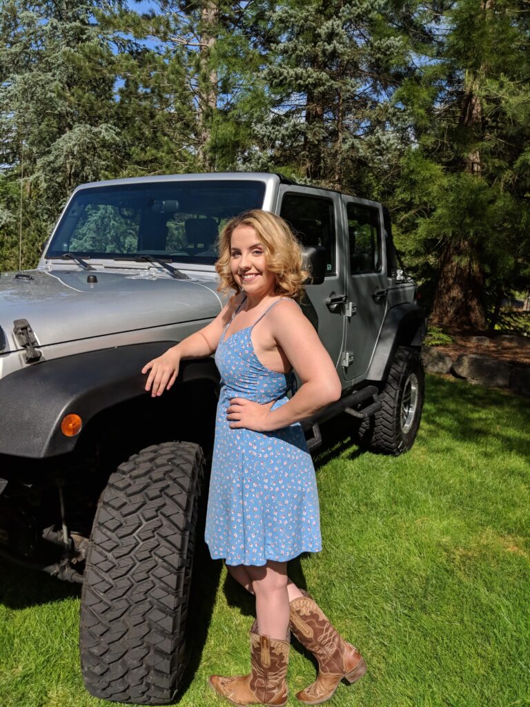 woman in blue sundress leaning on SUV