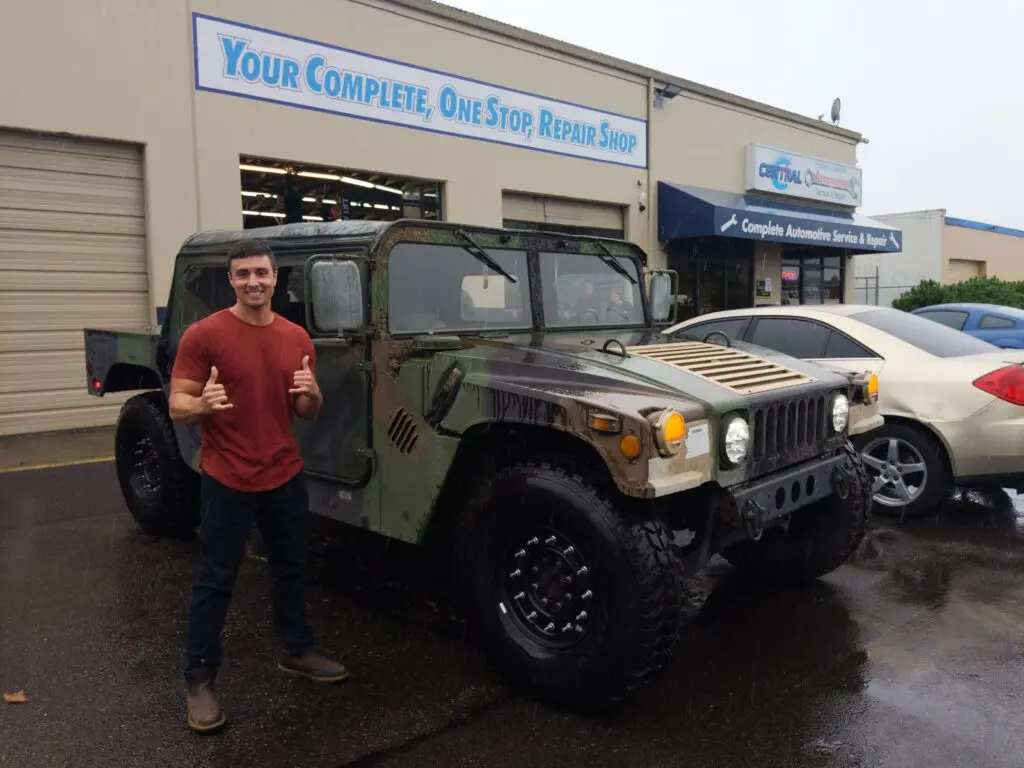 man posing next to old military SUV