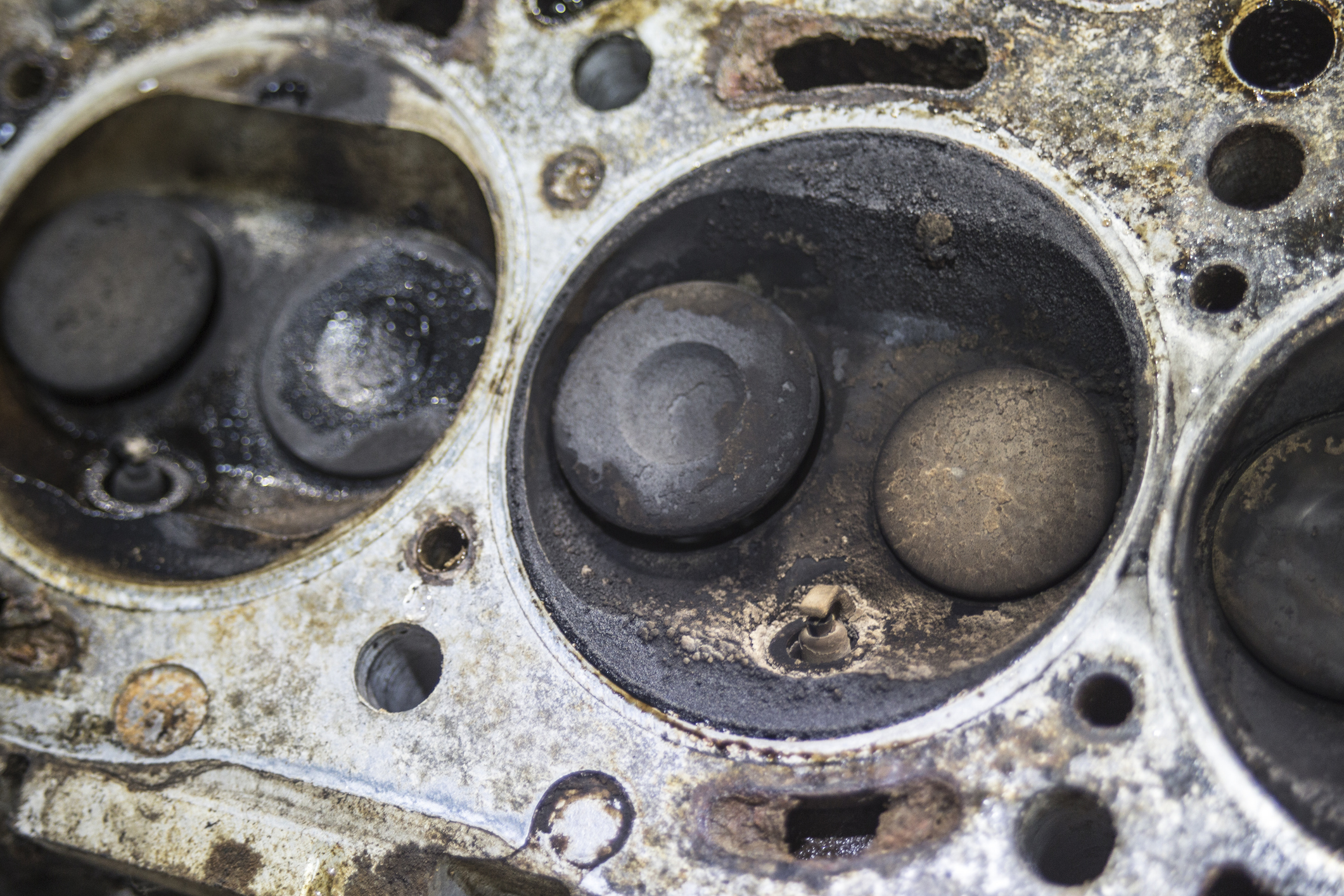Close-up of a car engine's cylinder block, with build-up around the valve heads